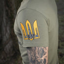 Close-up of olive green M-TAC military style t-shirt sleeve with yellow Ukrainian flag emblem and tattooed arm visible