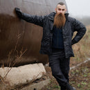 Man wearing original British Military Police waterproof lined rain jacket outdoors in rugged terrain on a rainy day