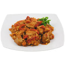 Cooked Serbian pork meat with rice and vegetables served on a white plate with a parsley garnish