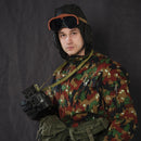 Man wearing vintage Italian army tanker goggles with camouflage jacket and leather aviator helmet holding binoculars