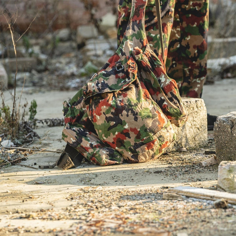 Swiss army Alpen camo backpack made of durable canvas, shown outdoors with suspenders and multiple compartments.