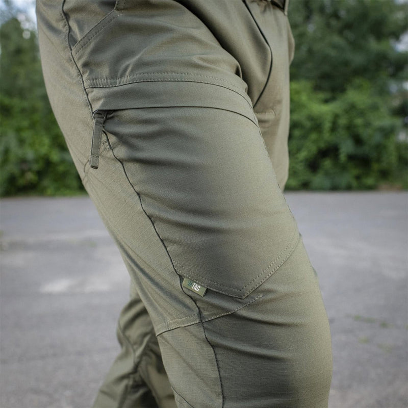 Close-up of olive green M-TAC military tactical pants with zipper pocket and reinforced stitching detail