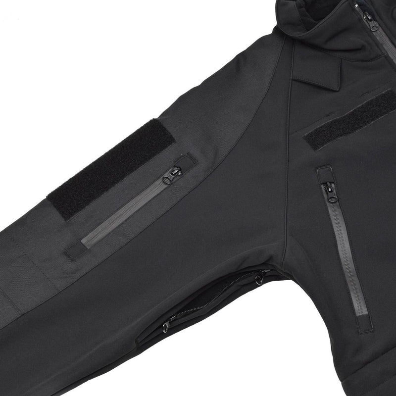 Close-up of black MIL-TEC softshell jacket sleeve with zippered pockets and vented armpits for breathability and water resistance.