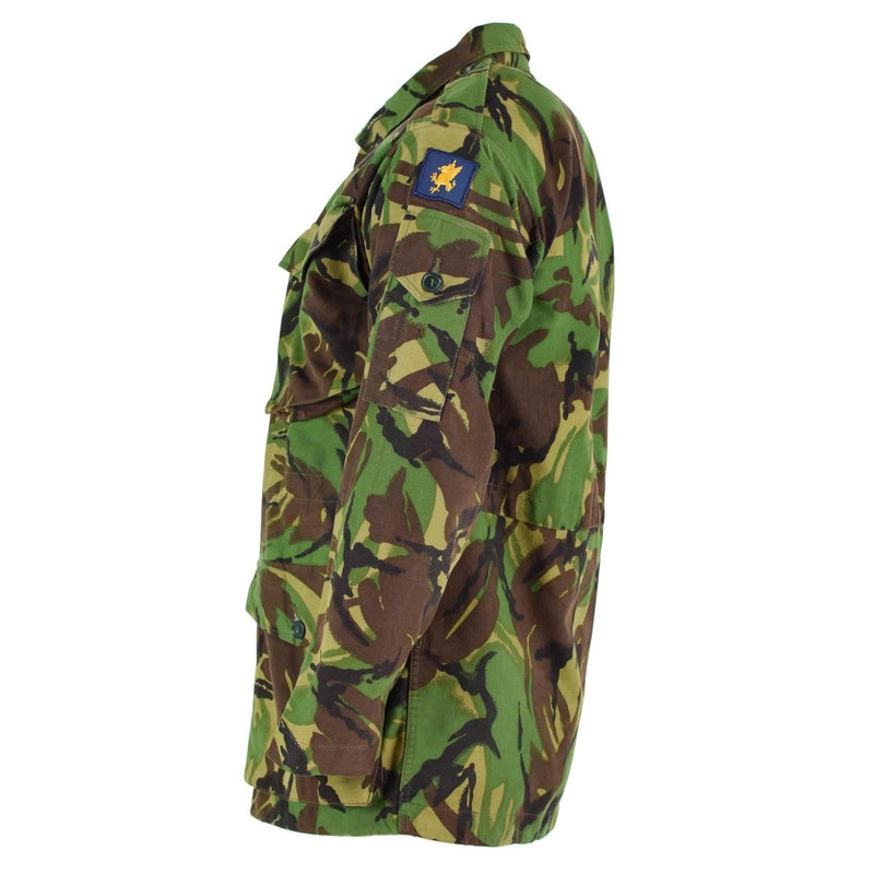 Side view of British army BDU combat smock jacket in woodland camo with patch on sleeve and multiple pockets.