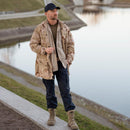 Man wearing original Dutch military work pants in navy blue with reinforced knees and cargo pockets outdoors near water